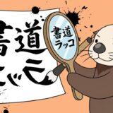 鏡文字で書いた半紙を手鏡で確認する書道ラッコ