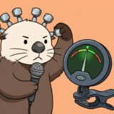 頭のペグを回して音程を合わせながらチューナーを見て歌うラッコ